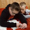 Zdjęcie przedstawia dwóch chłopców piszących list do Świętego Mikołaja.