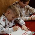 Zdjęcie przedstawia dwóch chłopców piszących list do Świętego Mikołaja.