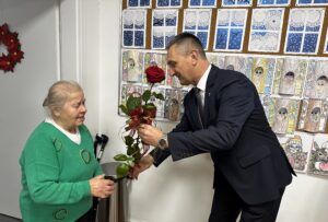 Zdjęcie przedstawia Wójta Gminy Przemęt, który wręcza Pani Janinie czerwoną różę.