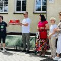 Na zdjęciu wójt wraz z Panią Elżbietą Witą trzymają w ręce czerwoną tabliczkę z białym napisem "strefa nadgraniczna". Koło wójta stoi Pani Monika Maćkowiak oraz Pani Dyrektor Małgorzata Zielińska.