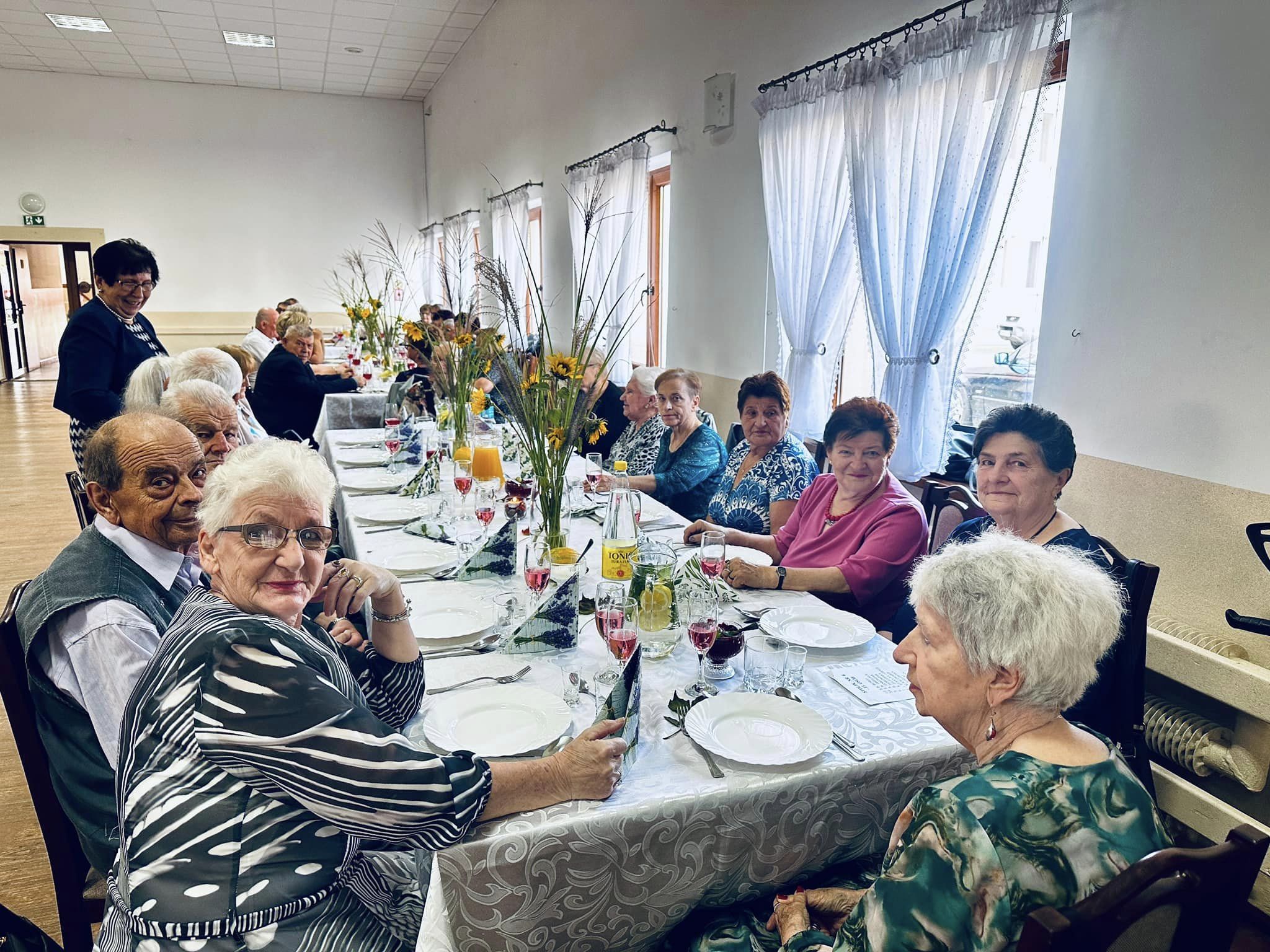 Zdjęcie przedstawia seniorów siedzących przy stole.