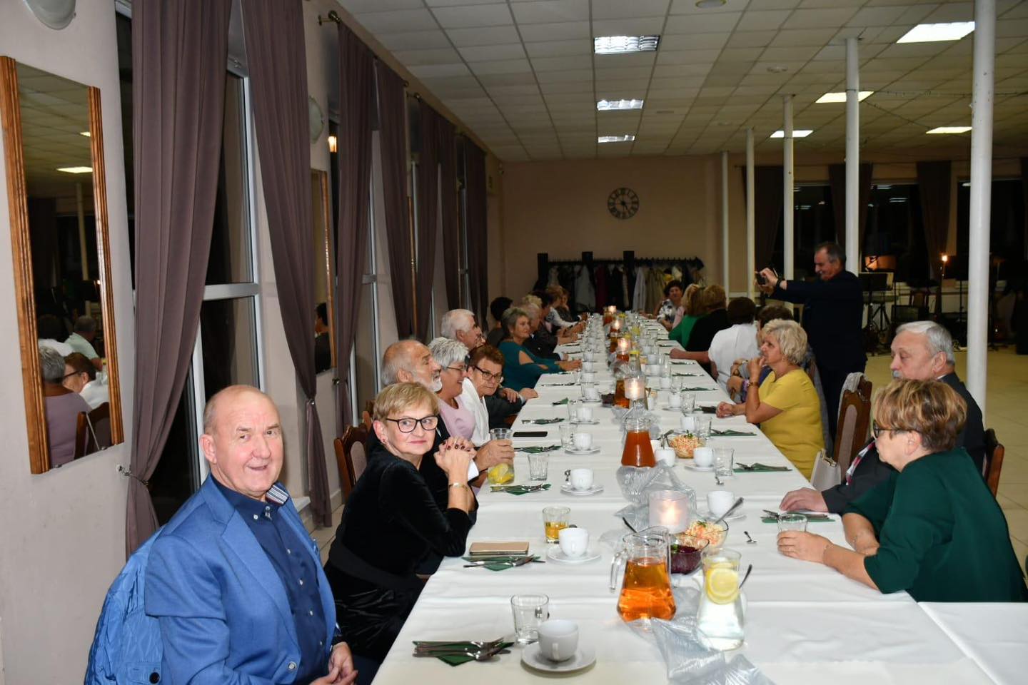 Na zdjęciu seniorzy siedzący przy stołach podczas uroczystości.