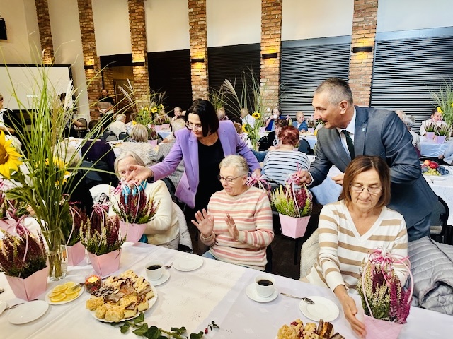 Na zdjęciu wójt wraz ze skarbnikiem gminy wręczają seniorom upominki - wrzosy.