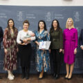 Wspólne zdjęcie, na którym znajduje się mama wraz z dzieckiem. Na fotografii także wójt, przewodnicząca rady gminy, przedstawicielka Zarządu Powiatu Wolsztyńskiego Patrycja Pabich, Kierownik Urzędu Stanu Cywilnego Leszek Anglart, Zastępca Kierownika Urzędu Stanu Cywilnego Irena Mikołajczak oraz pracownik urzędu. Wszyscy pozują na dużej szarej ściance, która zawiera herb gminy Przemęt oraz napisy "Gmina Przemęt".