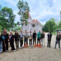 Wspólne zdjęcie uczniów, którzy pozują z grabiami. W tle pałac w Buczu.