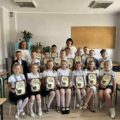 Wspólne zdjęcie uczniów jednej z klas wraz z dwiema nauczycielkami. Uczniowie pozują z dyplomami.