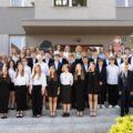 Grupowe zdjęcie uczniów z dyrektorką i nauczycielami wykonane przed wejściem do szkoły.