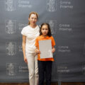 Na fotografii mama z synem, który trzyma nagrodę wójta. Pozują na tle szarej ścianki z rozmieszczonymi na niej herbem gminy Przemęt oraz napisem "Gmina Przemęt".