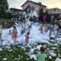 Na zdjęciu dzieci podczas zabawy w piana party. Na fotografii widoczne także osoby dorosłe.