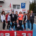 Na zdjęciu widoczne są kobiety po zakończonym biegu. Pozują z medalami, a jedna z nich trzyma w ręce puchar. Na fotografii obecny jest także wójt. Przed nimi znajduje się sportowe podium.