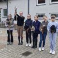 Na fotografii uczennice szkoły pozują do zdjęcia z końmi na patyku, które są wykorzystywane w dyscyplinie sportowej hobby horse.