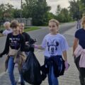 Na fotografii widać dziewczyny, które idą chodnikiem z workiem na śmieci.