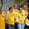 Na fotografii uczestnicy warsztatów podczas występu na scenie. Wszyscy uczestnicy mają żółte bluzki.
