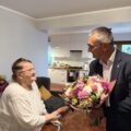 Na zdjęciu wójt wręcza jubilatce bukiet kwiatów.