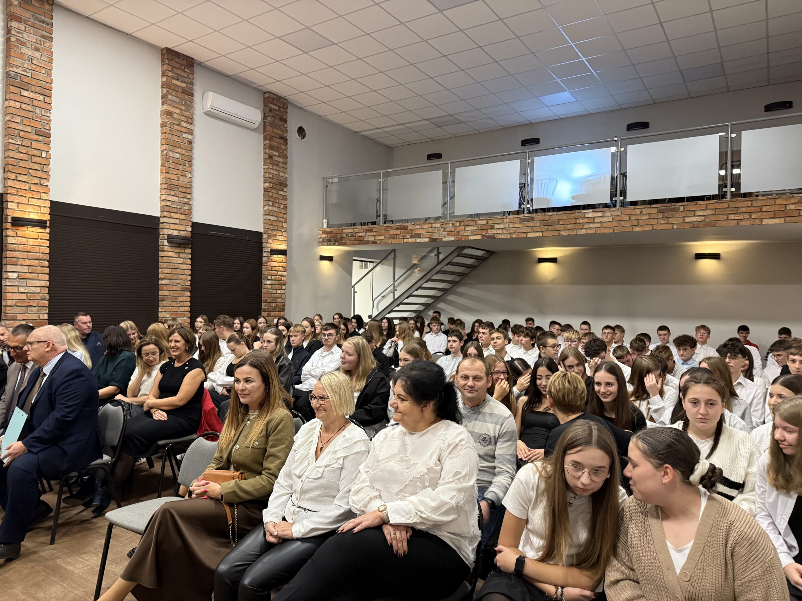 Na zdjęciu uczniowie oraz nauczyciele siedzący na widowni podczas uroczystości.