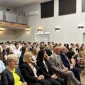 Na fotografii widoczne osoby siedzące na widowni, wśród nich m.in.: wójt Janusz Frąckowiak, dyrektor szkoły Roman Smoczyk, wicedyrektor szkoły Joanna Kalitka, kierownik wydziału Promocji i Turystyki Patrycja Pabich oraz przewodnicząca rady rodziców Ilona Matysik. W tle uczniowie i nauczyciele.