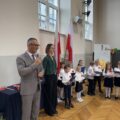 Na zdjęciu widoczny wójt podczas przemowy. Na fotografii także wychowawczyni jednej z klas oraz pierwszoklasiści.