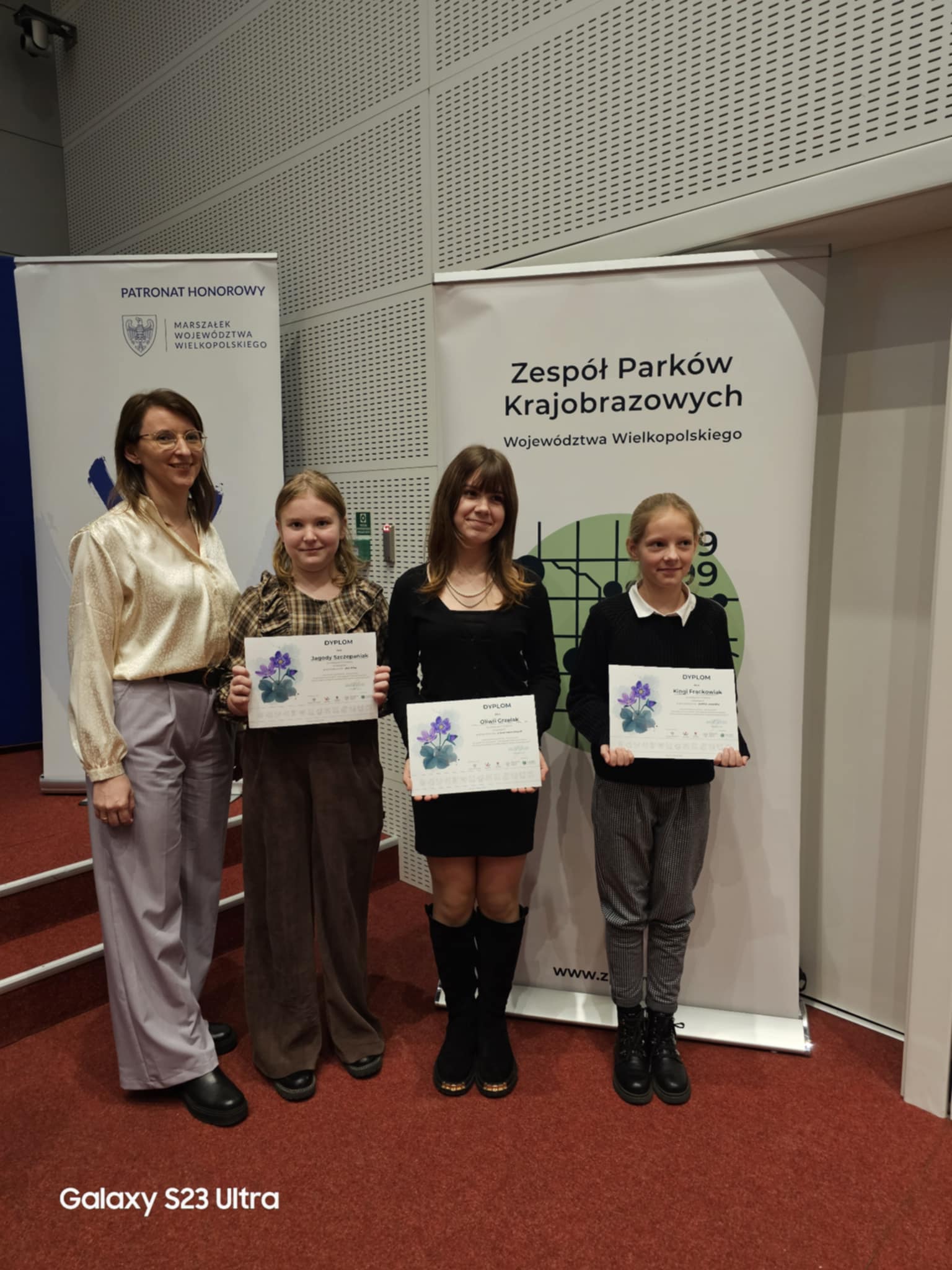 Na fotografii trzy uczennice wraz z nauczycielką. Uczennice pozują z dyplomami.