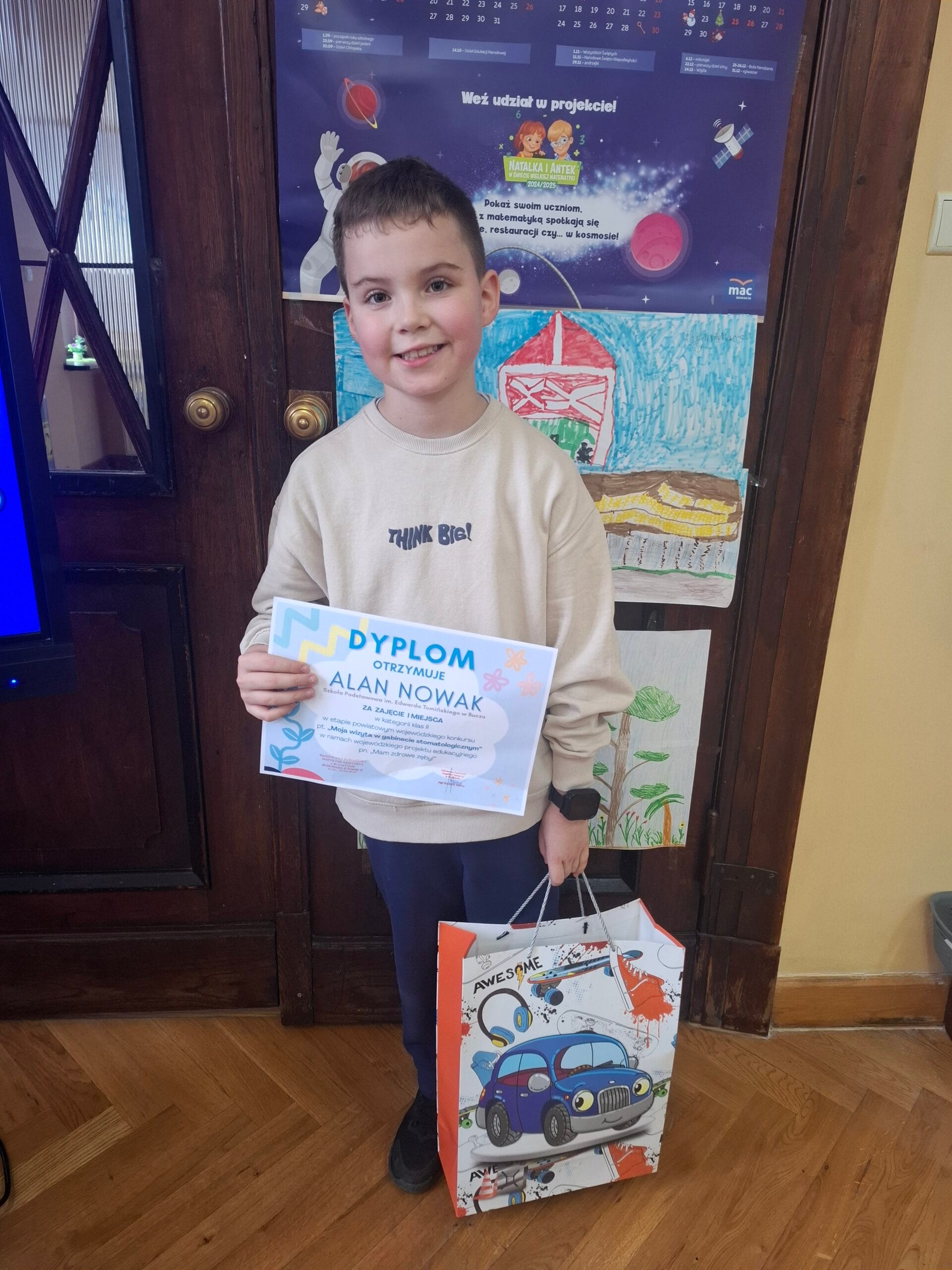 Na fotografii uczeń pozujący z nagrodą i dyplomem.